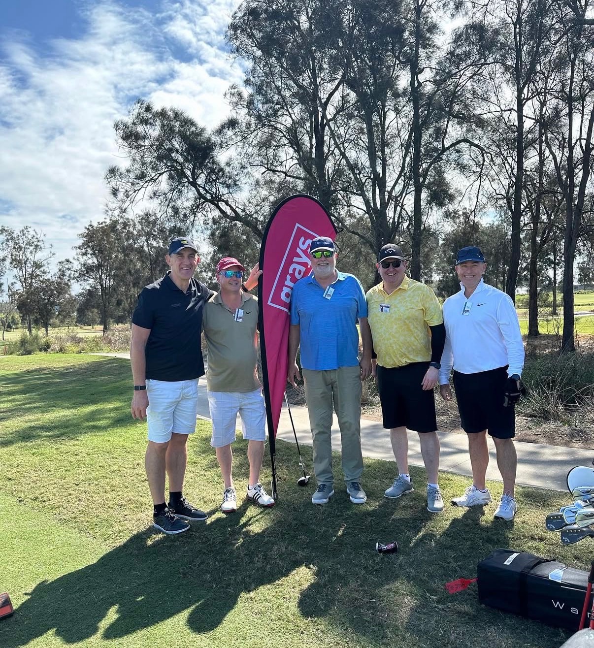 Players gathered beside event branding on the course