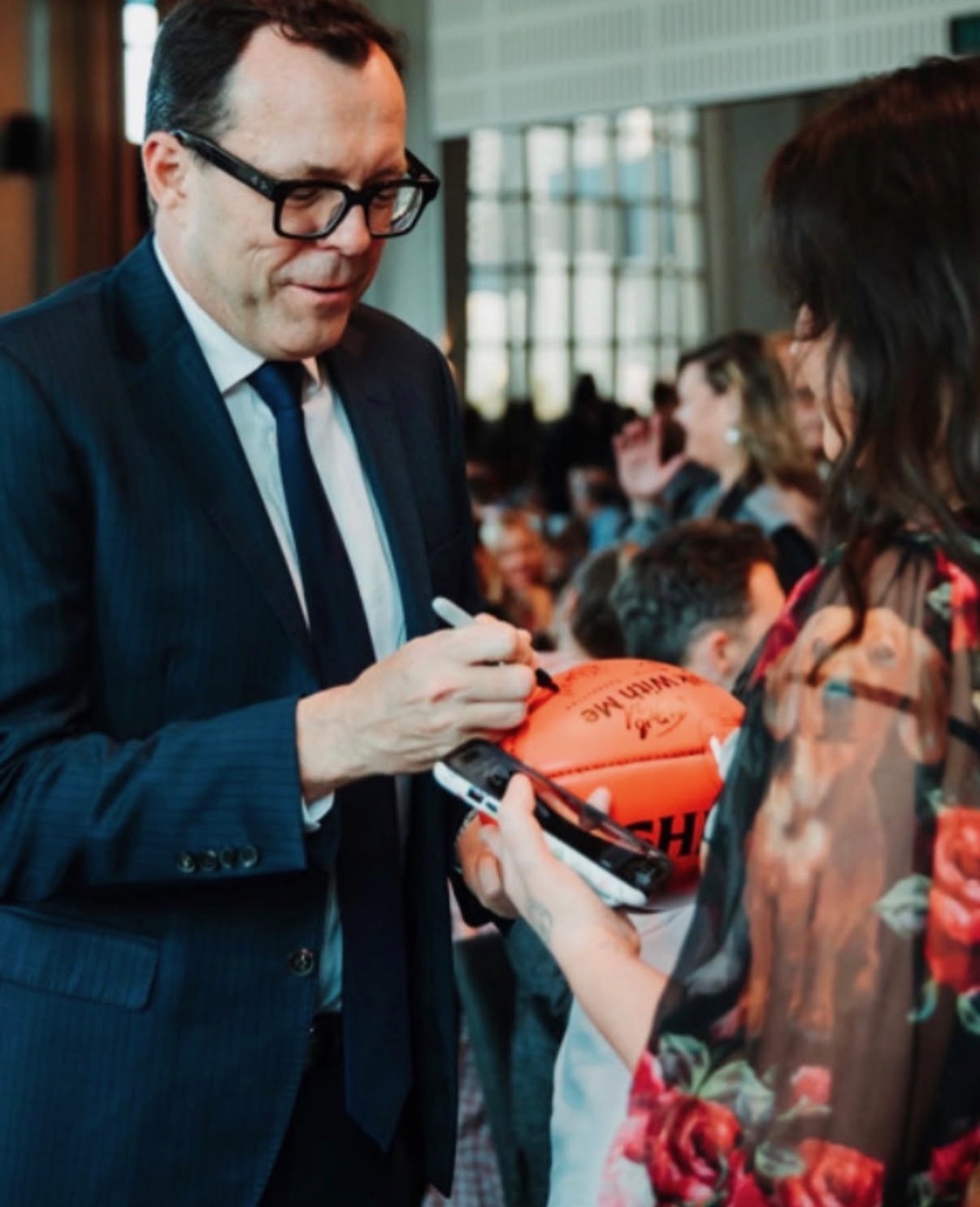 Guest signing a football for an attendee