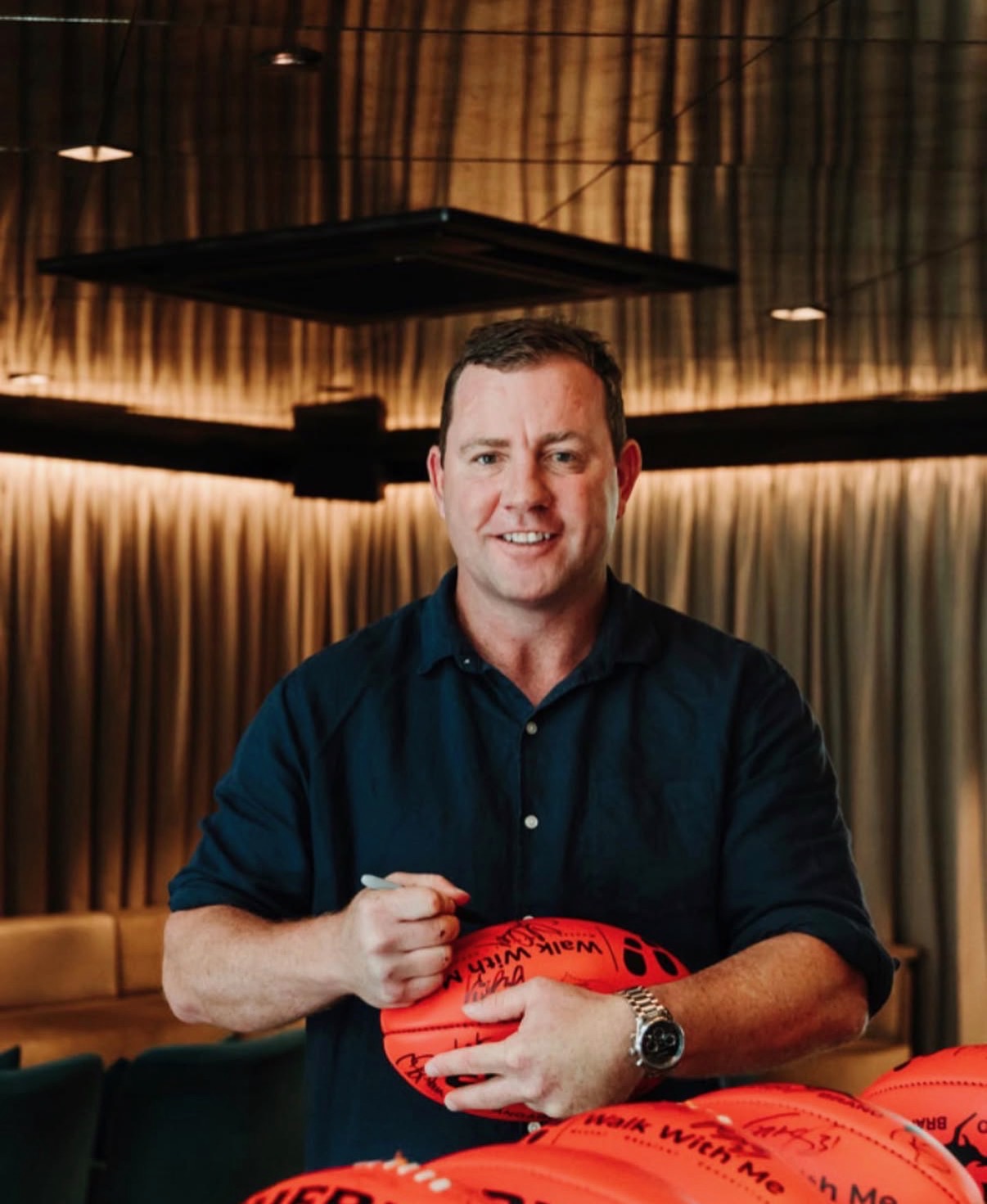 AFL personality signing footballs at a 4QTR event